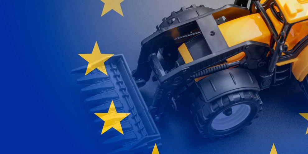 Ein Spielzeugtraktor fährt über die EU-Fahne.
