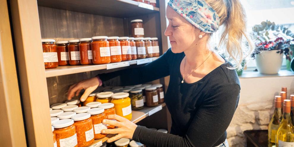 Die Bäuerin räumt Regale in ihrem Hofladen ein. 