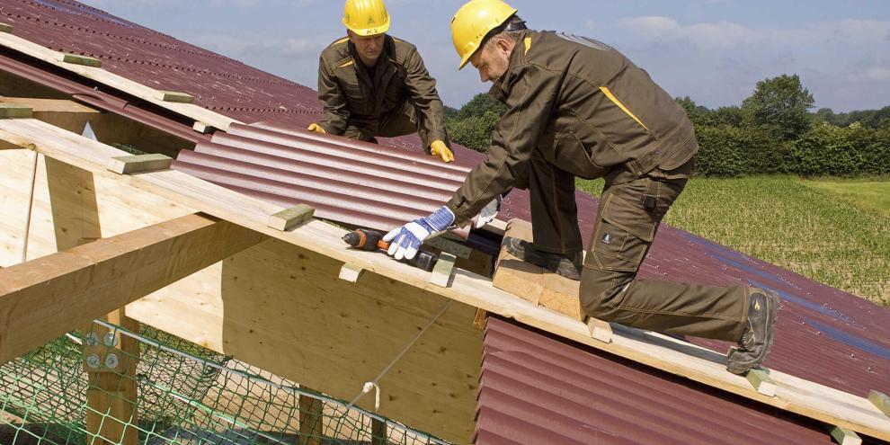 Zwei Männer mit Helm reparieren ein Dach