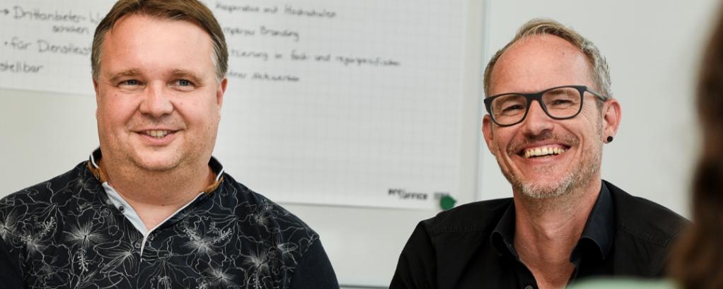 Vier Kollegen sitzen in einem Besprechungsraum und befinden sich in einem guten, unterhaltsamen und informativen Gespräch.