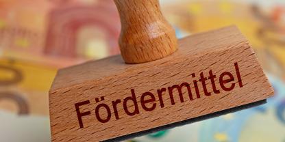 Stempel mit der Aufschrift Fördermittel vor Geldscheinen