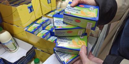 Eine Kundin hält Butterpäckchen bei Lidl in der Hand.