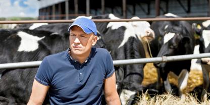 Ein Landwirt sitzt vor seinen Rindern.