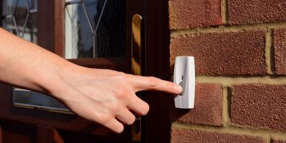 Eine Hand klingelt an einer Haustür