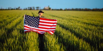 Eine Frau steht mit einer US-Flagge in einem Feld