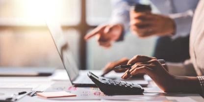 Eine Frau arbeitet am Laptop, ein Mann zeigt mit dem Finger auf den Bildschirm.