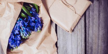 Geschenk in Kraftpapier mit Blumen auf rustikalem Holztisch als Symbol für praktische Valentinstag-Geschenke für Landwirte.