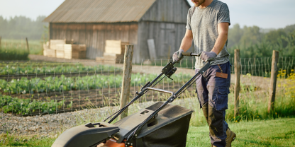 Landwirt mäht Hof mit Husqvarna Benzin-Rasenmäher. (Symbolbild erstellt mit KI)