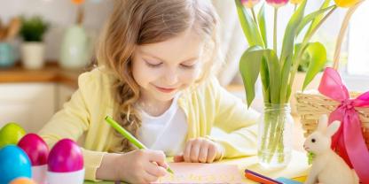 Ein Mädchen malt dem Osterhasen ein Bild.