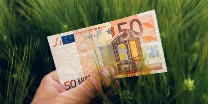 Ein Mann hält einen 50-Euro-Schein vor Gerste in die Kamera