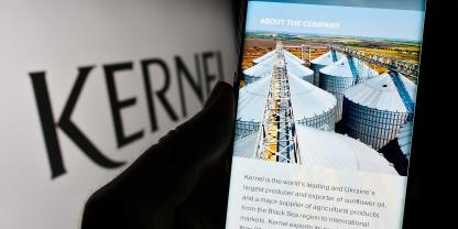 Das Logo von Kernel auf einem Bildschirm, davor ein Handy mit Getreidesilos im Display.