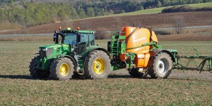 Ein Landwirt bringt mit dem Traktor Pflanzenschutzmittel aus.