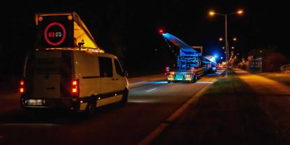 Ein Schwertransporte bei Nacht mit einem Windrad