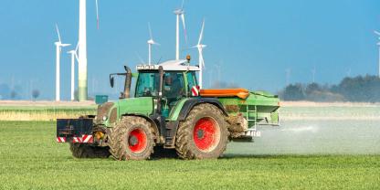 Ein Landwirt bringt mit dem Traktor Mineraldünger aus.