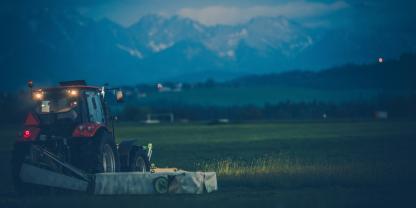 Traktor mäht Wiese bei Nacht