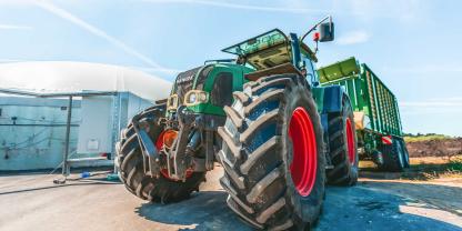 Ein Fendt Traktor mit Ladewagen vor einem Silo