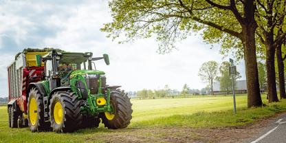 Neuer Traktor John Deere 6R fährt vom Feld auf die Strasse.