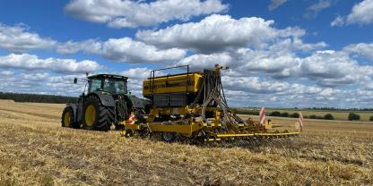 Traktor mit Direktsaatmaschine vor blauem Himmel