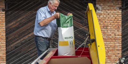 Ein Landwirt füllt Saatgetreide in die Drillmaschine.