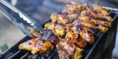 Geflügeteile werden auf einem Grill zubereitet.