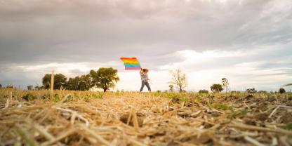 Ein Mann mit Regenbogenflagge auf einem Acker