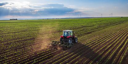 Ein Landwirt fährt mit dem Traktor über ein Feld.