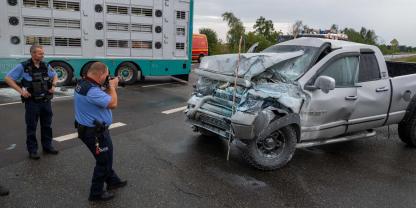 Polizeibeamte nehmen den Unfall auf: Der Geländewagen hatte nach dem Zusammenprall zu brennen begonnen.