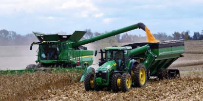 Ein Häcksler und ein Traktor von John Deere bei der Maisernte.