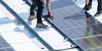 Handwerker installieren Solarmodule auf einem Dach.