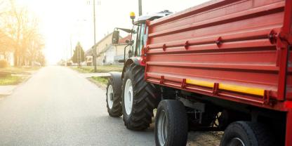 Traktor mit einem Anhänger fährt auf einer Strasse.