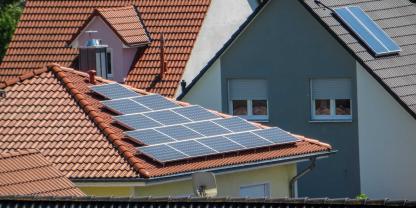 Hausdächer mit und ohne Solaranlage in einer Siedlung: Von Solarstrom profitieren nicht nur Haushalte mit einer eigenen Solaranlage.