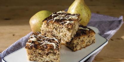 Schokokuchen mit Birnen vom Blech angerichtet auf einer Kuchenplatte.