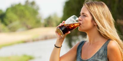 Eine junge Frau trinkt ein Glas Cola.