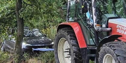 Ein Steyr Traktor zieht einen Tesla aus dem Wald